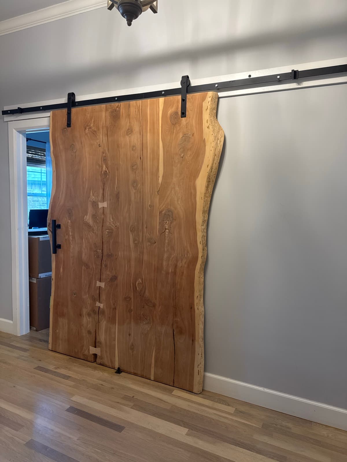 Custom live-edge wood sliding barn door mounted on a black steel rail over an interior doorway