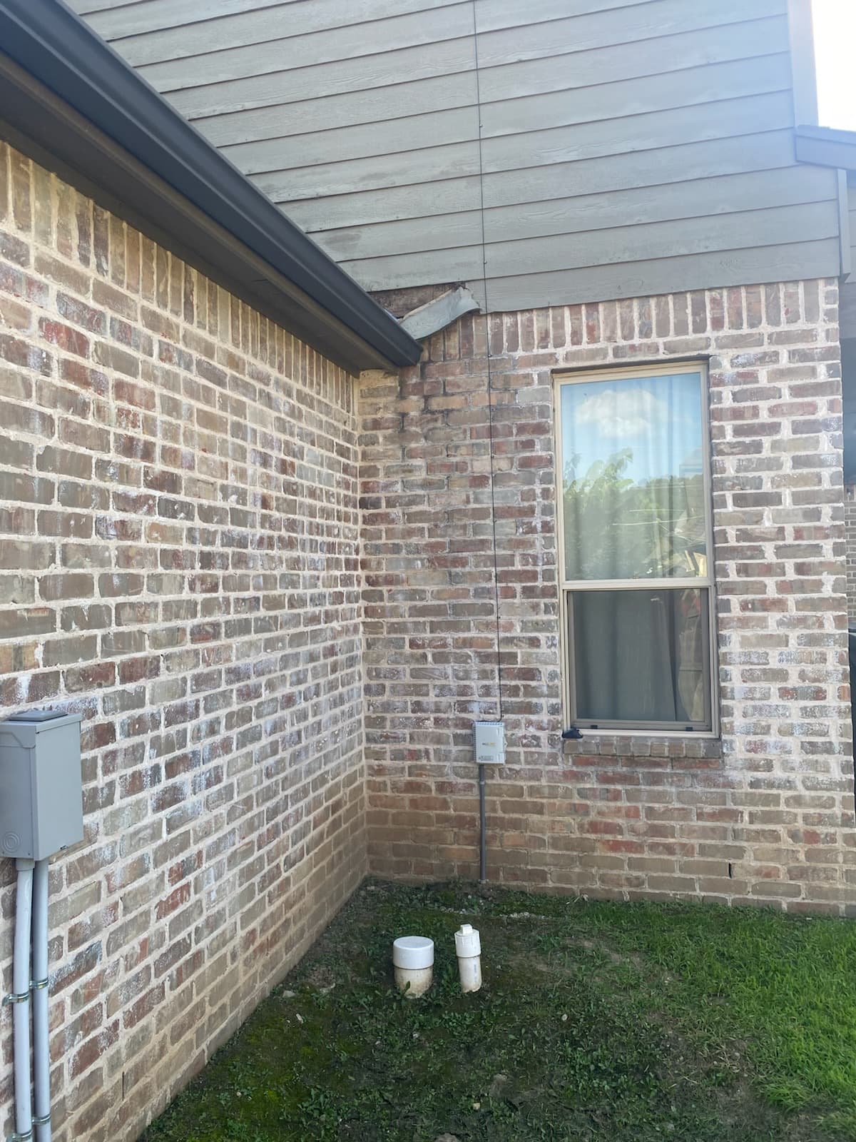 Repaired soffit and lap siding above a brick exterior wall corner on a Bixby home